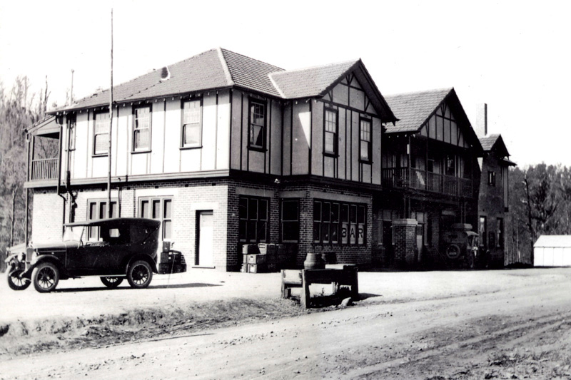 The Noojee Hotel, a two-storey mock-Tudor building, with a 1920s car parked out front on a dirt road